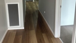 A hallway with a wooden floor, a vent on the left, and a door on the right. - Awesome Central Horsham Home (Horsham)