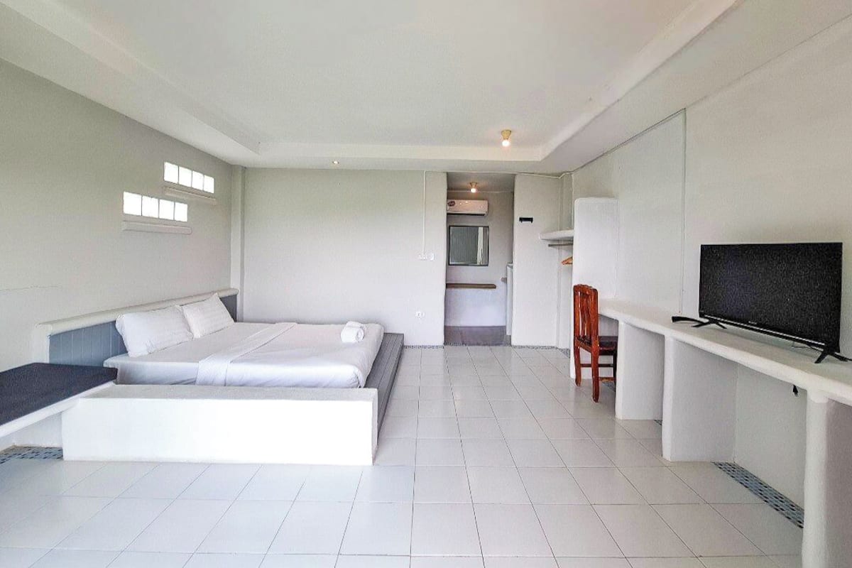 A modern hotel room with a large bed, a TV, and a small seating area.