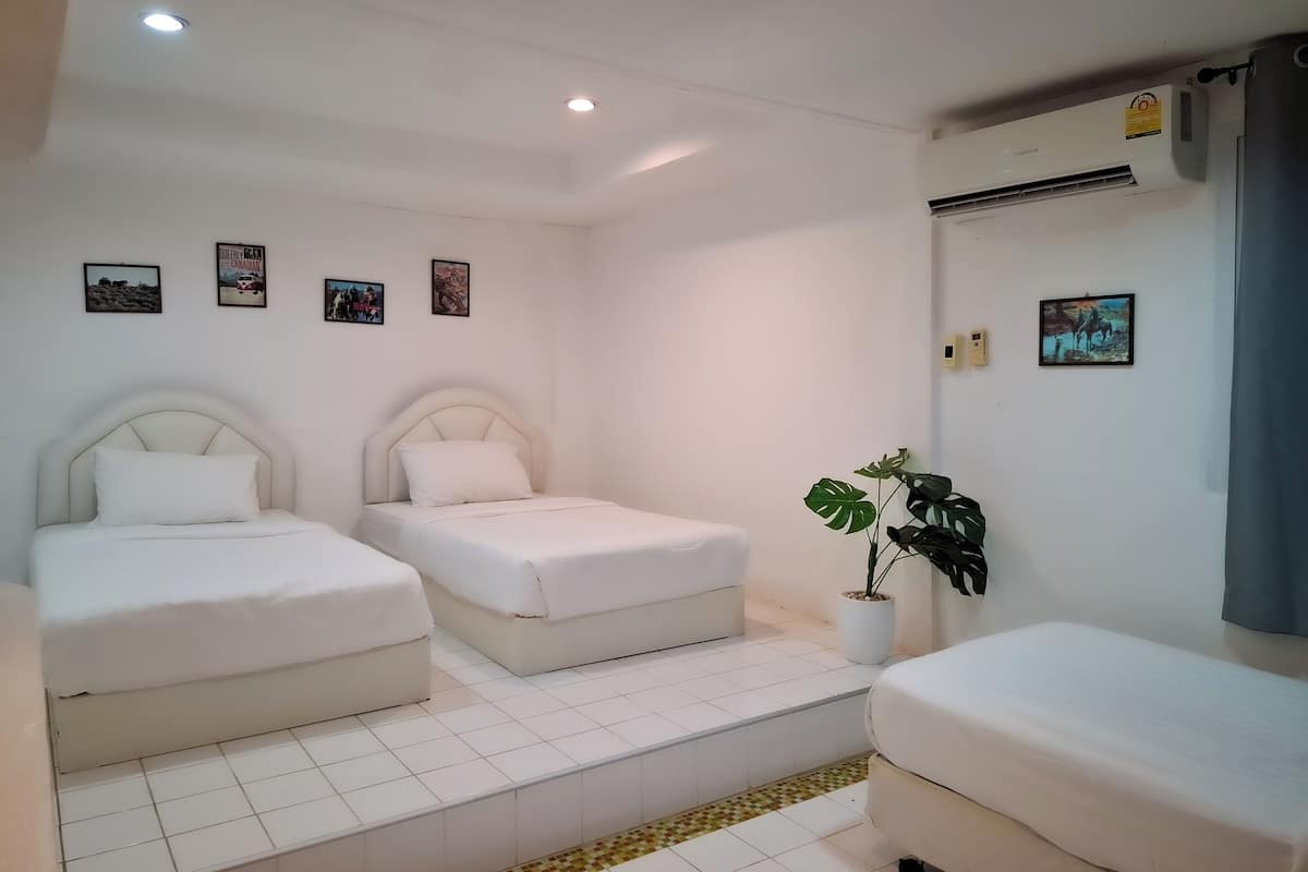A hotel room with two beds, a potted plant, and a tiled floor.