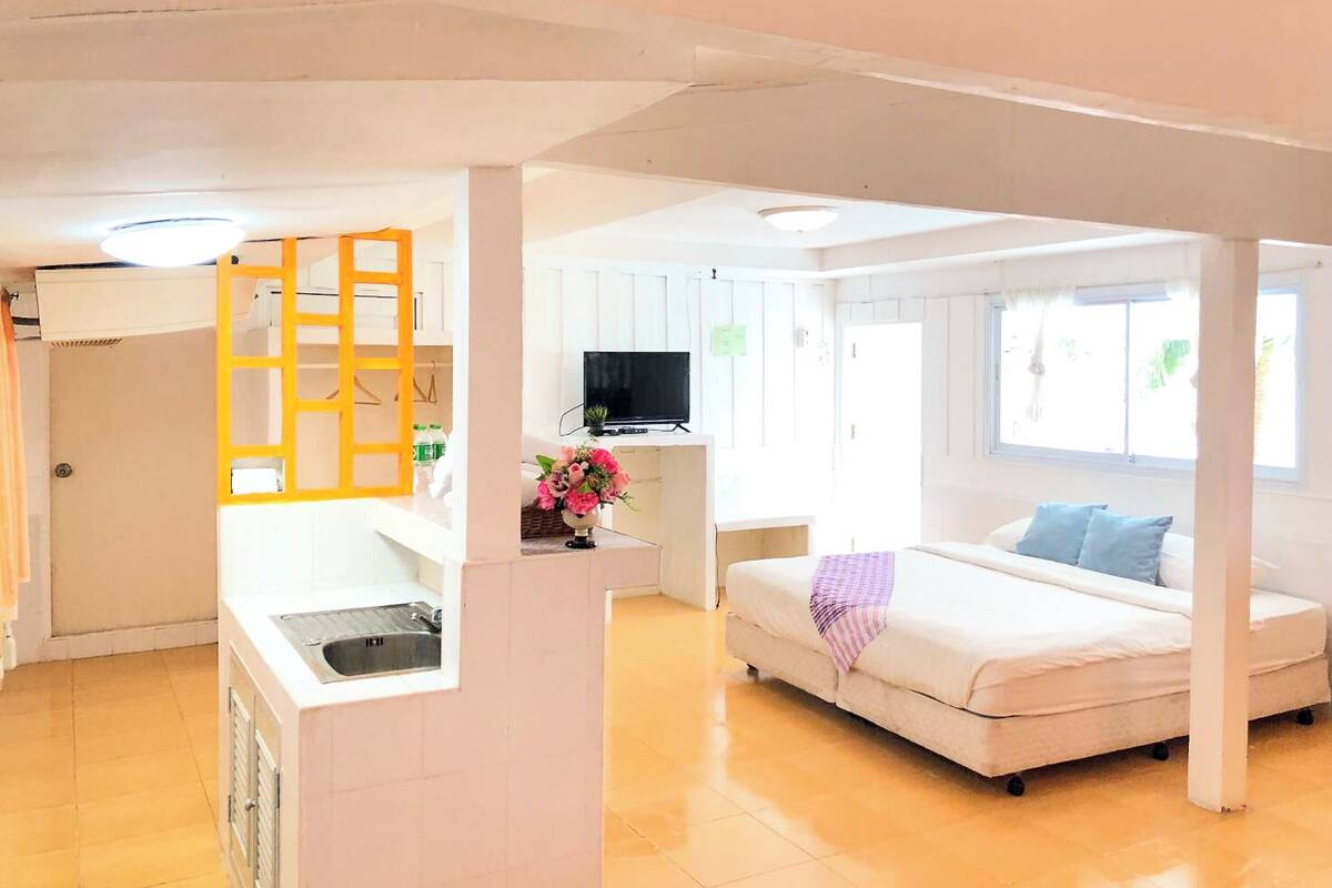 A compact living space with a kitchenette, a bed, and a TV.