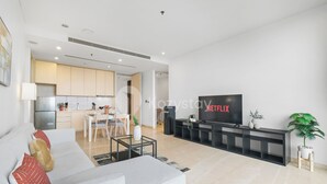 Een moderne woonkamer met een grijze bank, een salontafel en een televisie waarop 'NETFLIX' wordt weergegeven.