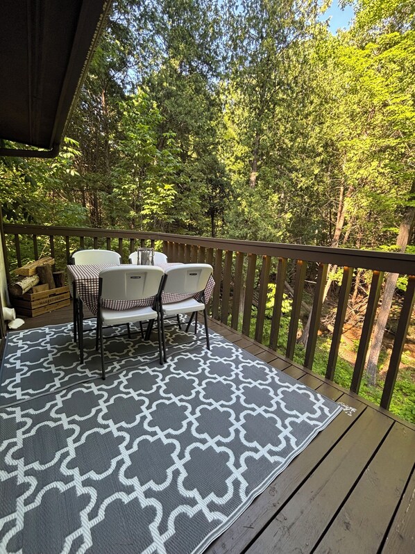 A wooden deck with a patterned rug, a table, and two chairs.