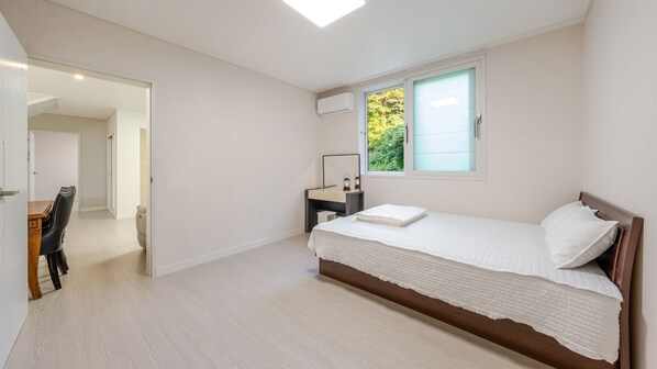 A bedroom with a bed, a desk, a chair, a window, and an air conditioning unit. - Gyeongju Sunflower Private Cottage (Gyeongju)