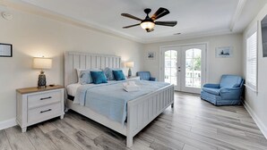A bedroom with a bed, nightstands, a chair, a ceiling fan, and a door leading to a balcony. - 4 BR Beach Retreat - 2 Suites - Dogs Welcome (Norfolk)