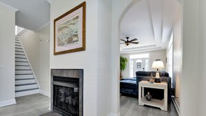 A spacious living area with a fireplace, a staircase, and a cozy seating area with a lamp. - 4 BR Beach Retreat - 2 Suites - Dogs Welcome (Norfolk)
