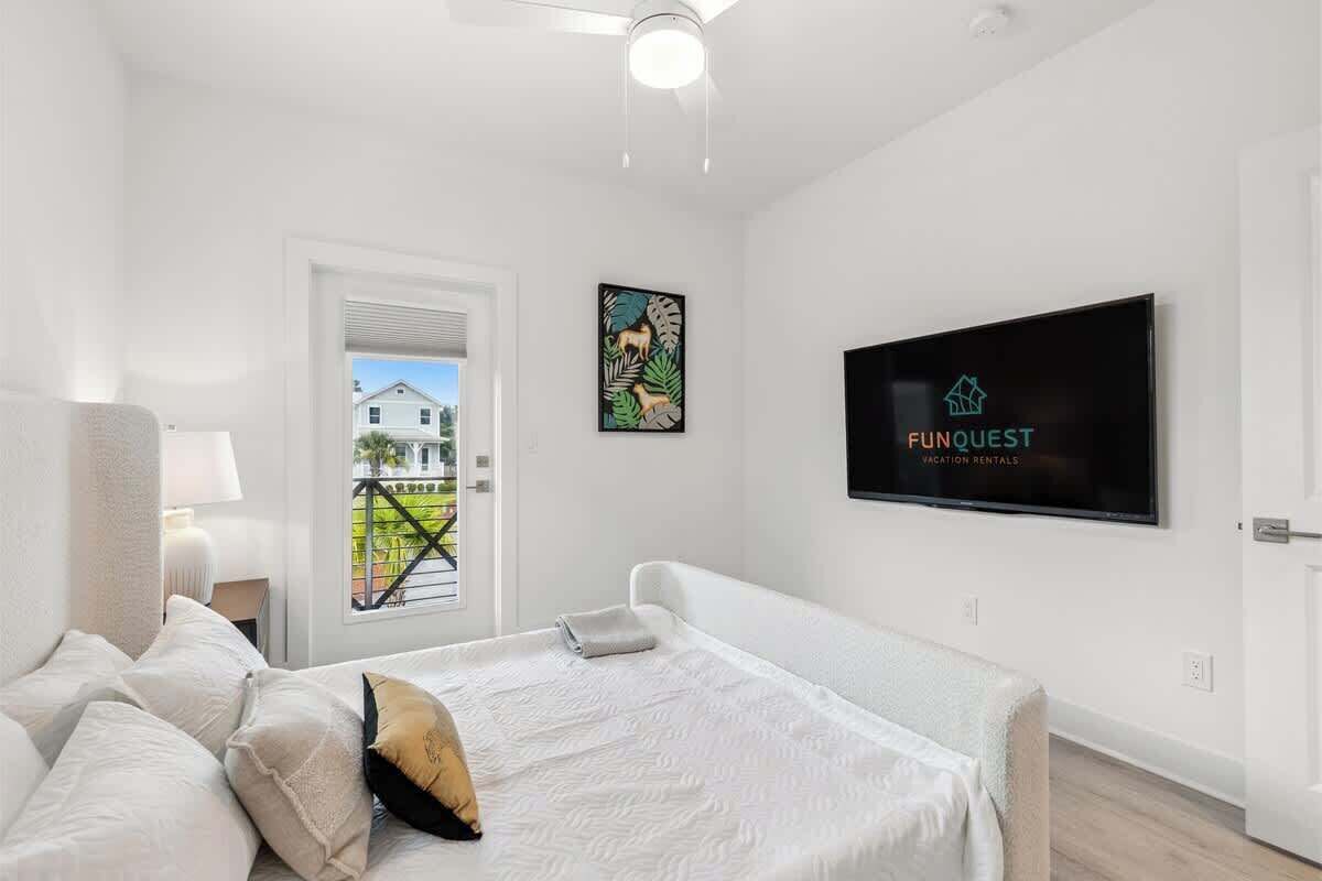 Habitación de hotel moderna con una cama grande, un televisor en la pared y un balcón con vistas a casas.