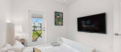 Habitación de hotel moderna con una cama grande, un televisor en la pared y un balcón con vistas a casas.
