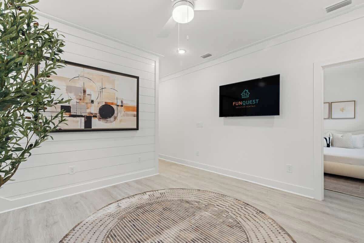 Une chambre d’hôtel moderne avec un grand tableau abstrait, un téléviseur à écran plat et un tapis en fibres naturelles.