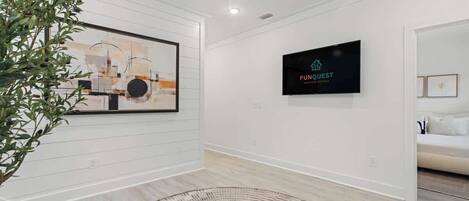 Une chambre d’hôtel moderne avec un grand tableau abstrait, un téléviseur à écran plat et un tapis en fibres naturelles.