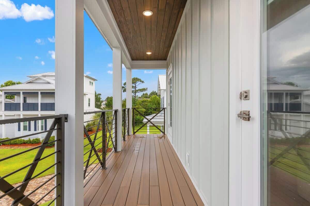 Un balcon fermé doté d’un plancher en bois, de murs blancs et offrant une vue sur les maisons voisines.