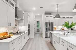 Una cocina moderna con armarios blancos, electrodomésticos de acero inoxidable y una isla central.