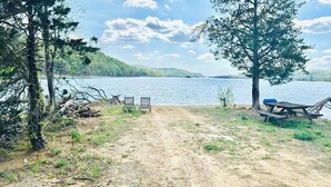 Un sendero de tierra que conduce a una zona junto al lago con dos sillas y una mesa de picnic.