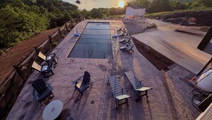 Piscina en la azotea con sillas de descanso y vista a un lago y colinas.