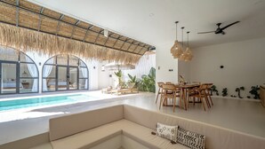 Un área de estar moderna con piscina, comedor y sofá.