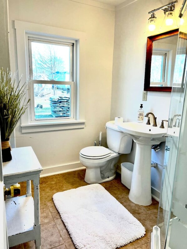 Une salle de bain avec des toilettes, un lavabo et une fenêtre.