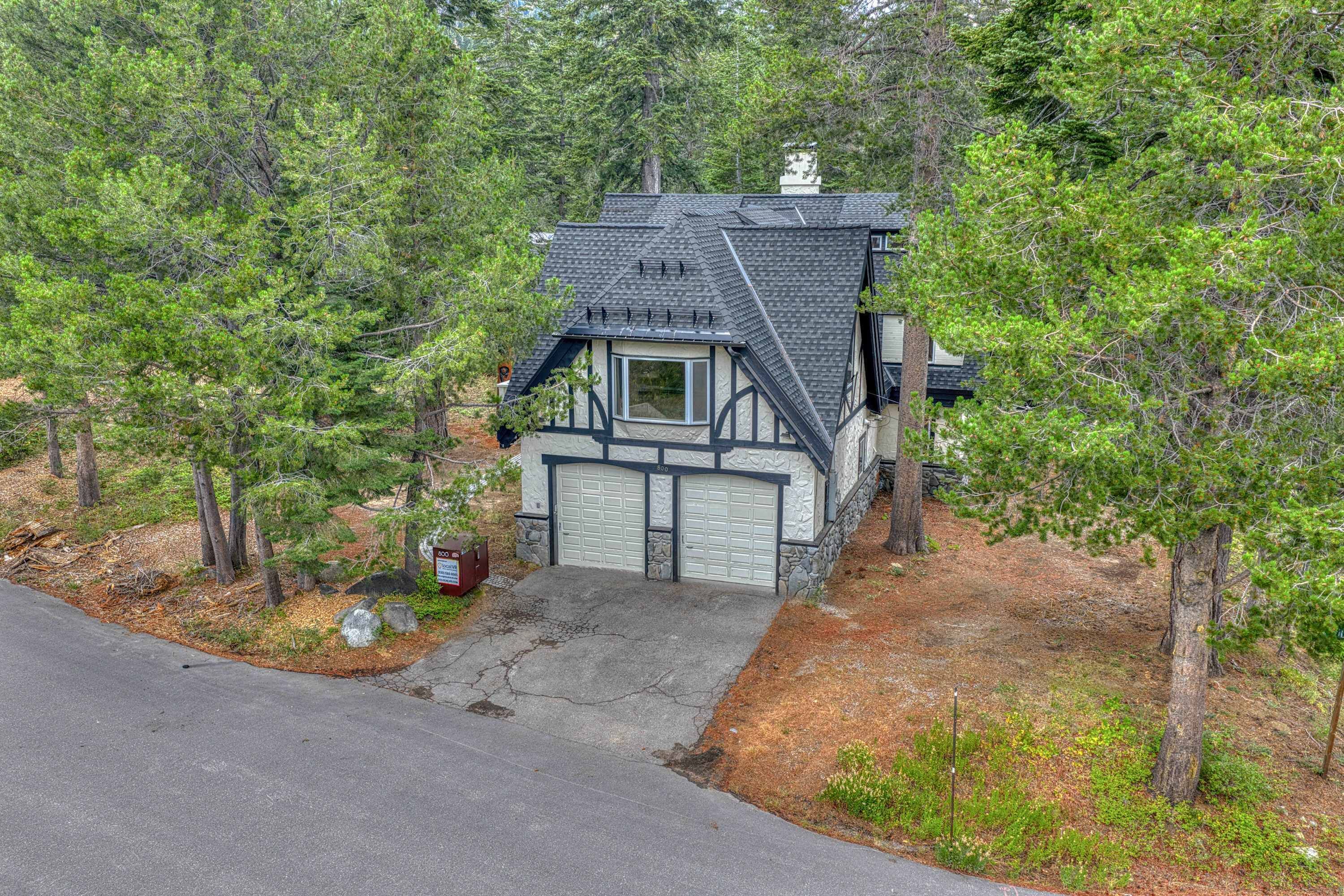 Une maison avec un toit à forte pente, un garage à l’avant et des fondations en pierre.