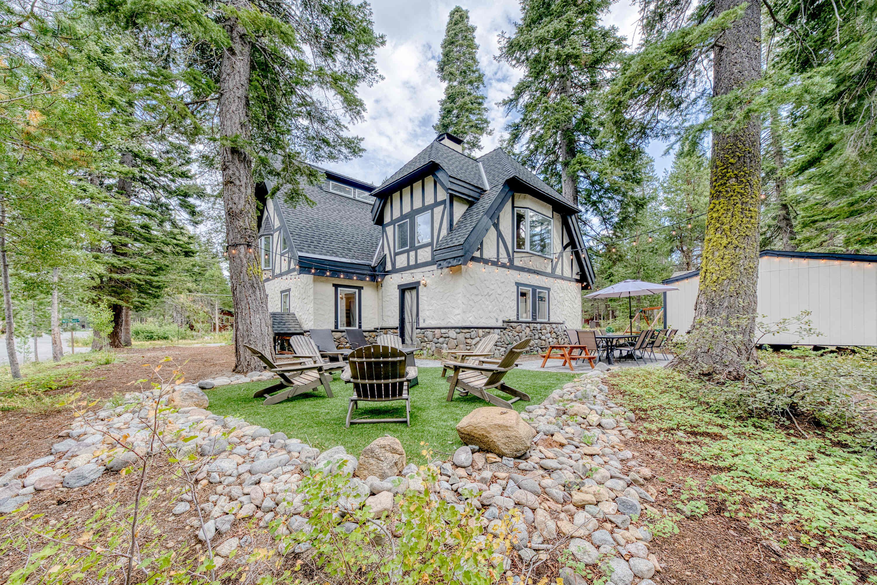 A two-story house with a stone facade, surrounded by a forest.