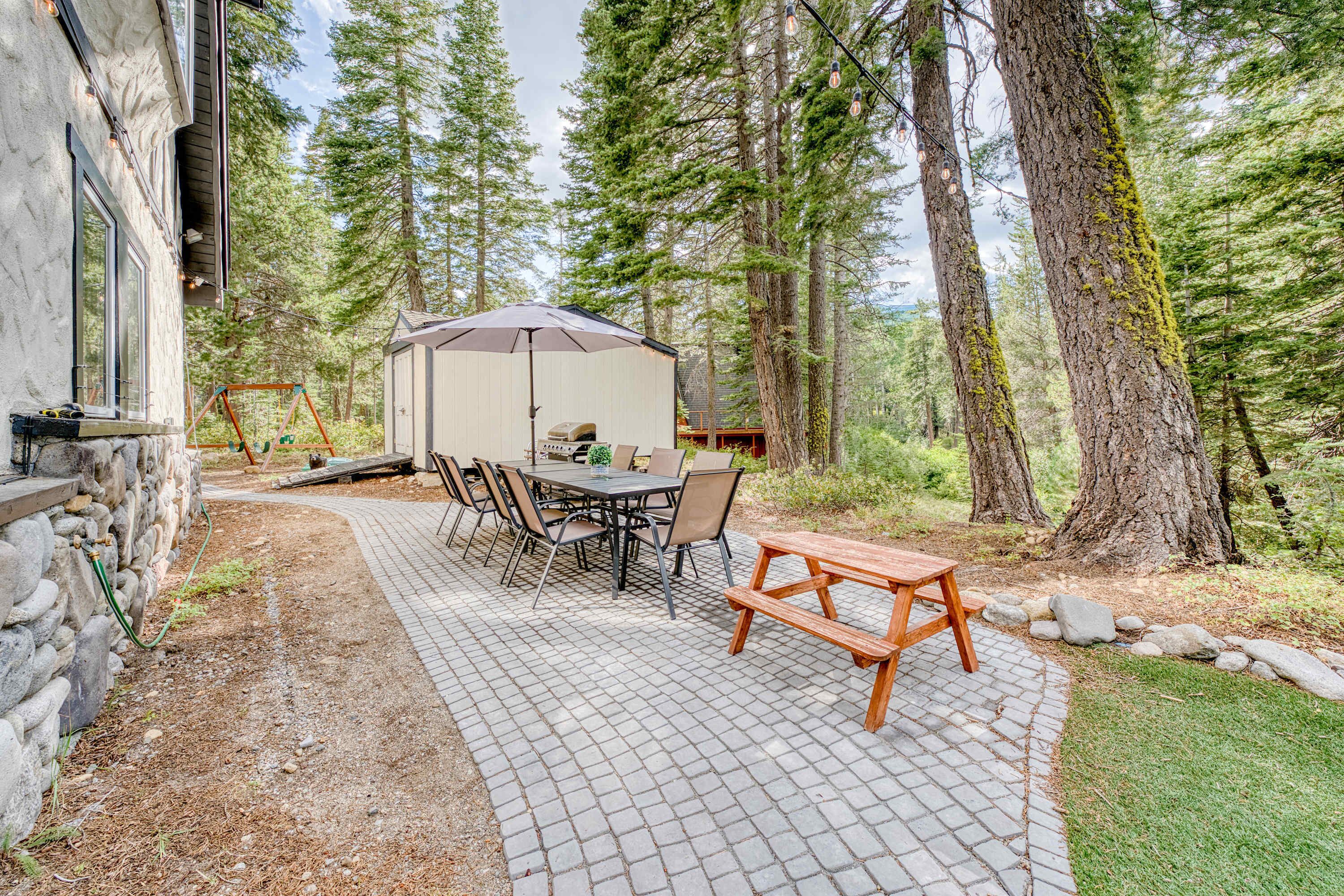 A patio area with a stone floor, picnic table, and umbrella.