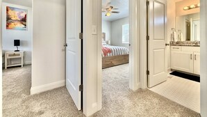 Un dormitorio con cama, ventilador de techo y ventana.