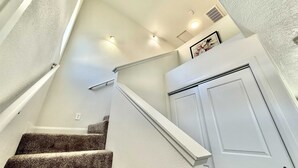 A staircase with carpeted steps, white walls, and a white door.