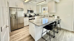A modern kitchen with stainless steel appliances, a granite countertop, and a bar area with stools.