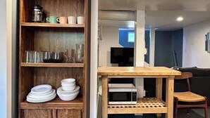Un espacio habitable compacto con un armario de madera, una mesa de comedor y un microondas.