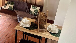 A cozy seating area with a sofa and cushions, a small table with a tray and plates, and a chair. - Cozy 1-bedroom apartment in adorable Tobago with AC, WiFi (Tobago)