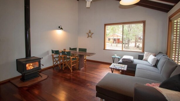 Un salón acogedor con chimenea, un comedor con mesa y sillas, un sofá y un amplio ventanal con vistas al exterior.