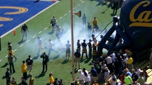 Un terrain de football avec des joueurs et du personnel, entouré de spectateurs.