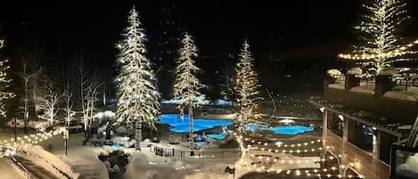 A snow-covered outdoor area with illuminated trees and a pool.