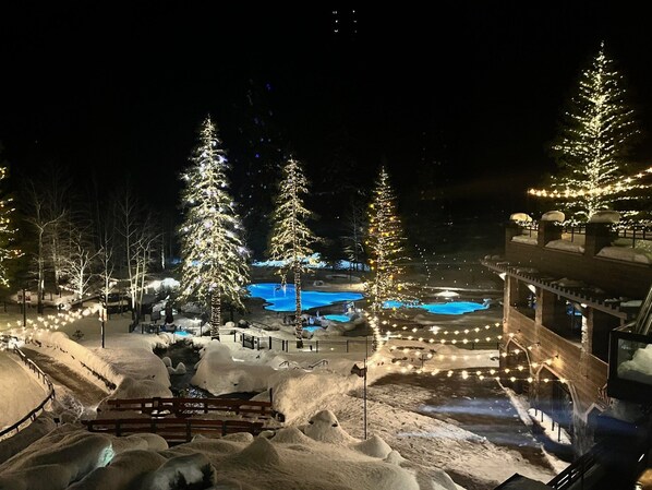 A snow-covered outdoor area with illuminated trees and a pool.