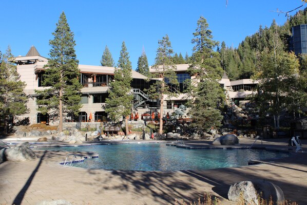 A resort with a pool, outdoor seating, and a mountainous backdrop.