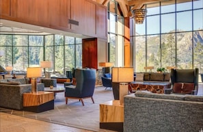 A spacious lobby with large windows offering mountain views, comfortable seating, and a modern chandelier.