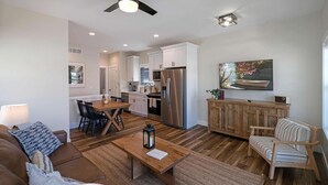 A modern kitchen with white cabinets, stainless steel appliances, and a dining area with a wooden table and chairs.