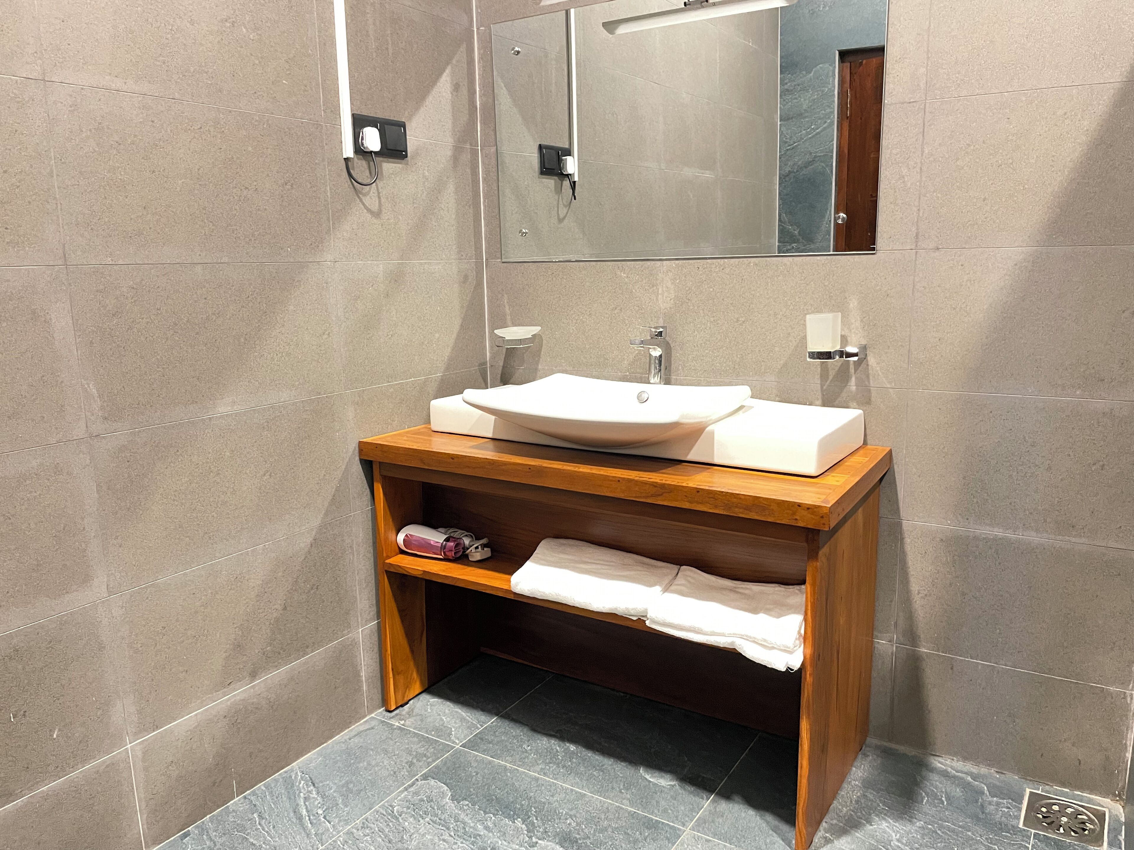Un bagno moderno con un mobile bagno in legno, lavandino bianco e uno specchio sopra.