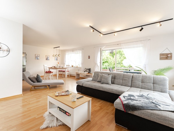 A modern living room with a sofa, coffee table, and a dining area with chairs. - Light-flooded vacation apartment Felix - your Allgäu dream in a quiet idyll (Weitnau)