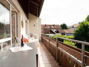 A balcony with a table set for dining, a hanging chair, and a view of neighboring houses. - Light-flooded vacation apartment Felix - your Allgäu dream in a quiet idyll (Weitnau)