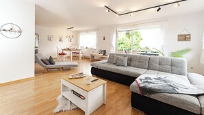 Un salon moderne comprenant un canapé, une table basse et un coin repas avec une table et des chaises.