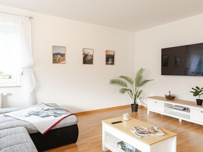 Un salon avec un canapé, une table basse, un téléviseur et des œuvres d’art murales.