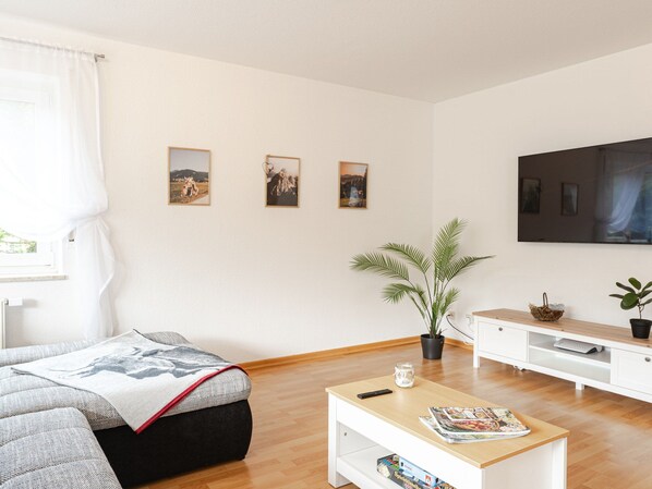 A living room with a sofa, coffee table, TV, and wall art. - Light-flooded vacation apartment Felix - your Allgäu dream in a quiet idyll (Weitnau)
