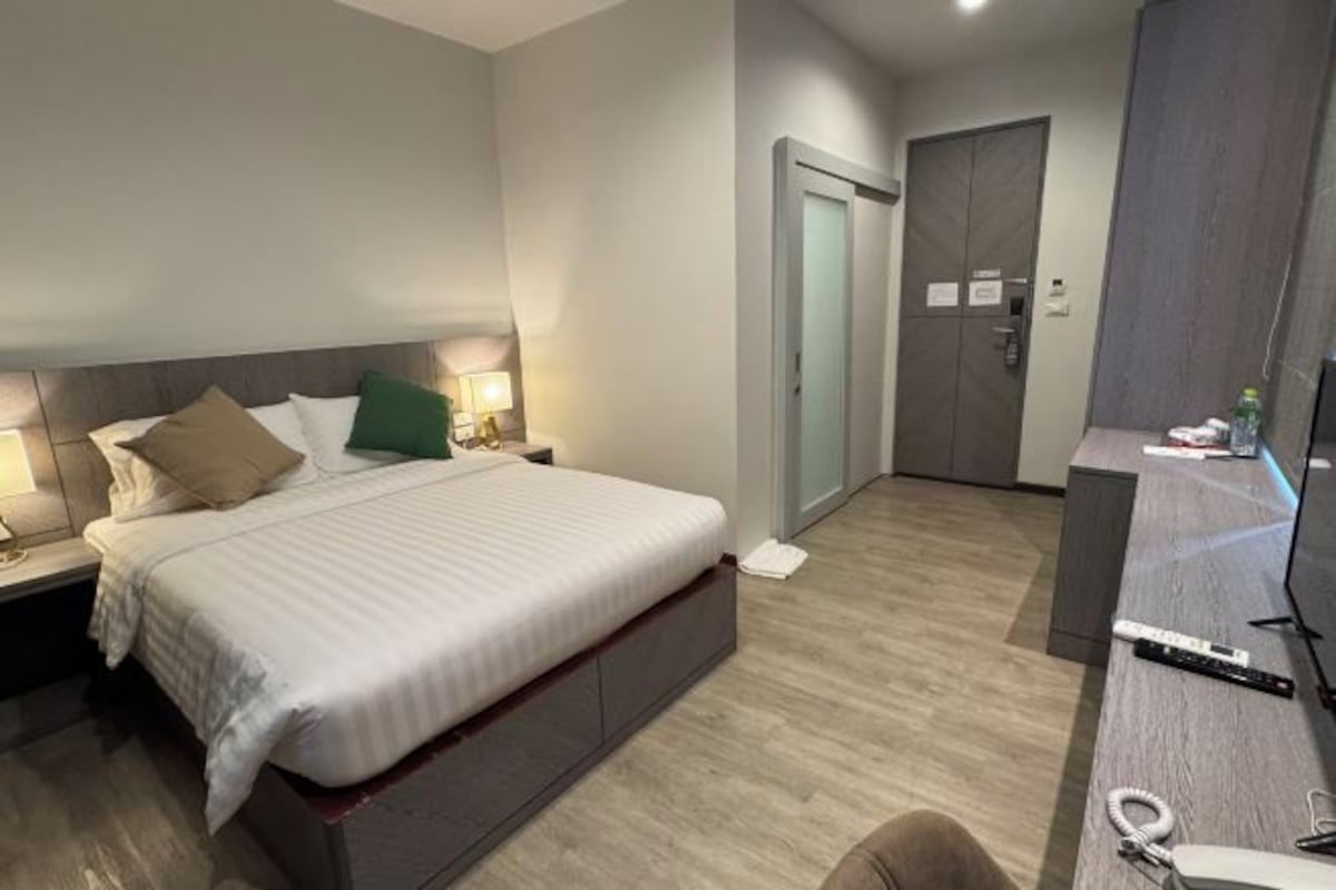 Una habitación de hotel con cama, mesitas de noche, escritorio y armario.