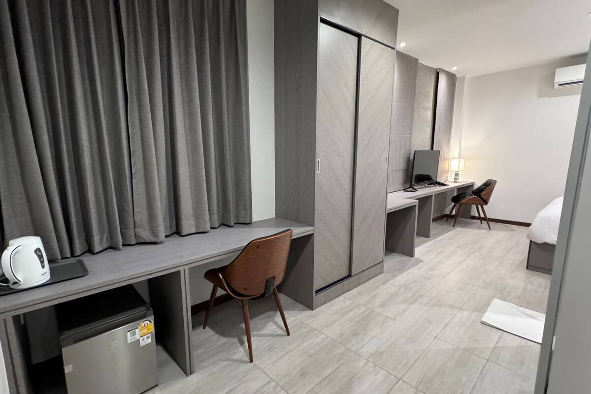 A modern hotel room with a desk, chair, and a bed.
