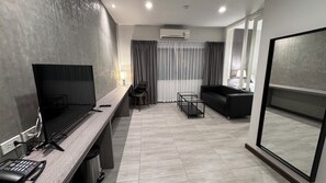 A modern hotel room with a flat-screen TV, a desk with a telephone, a sofa, and a glass table. - The Kite Hotel Bangkok (Bangkok)
