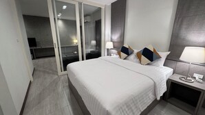 A modern hotel room with a large bed, a bedside table with a lamp, and a sliding door leading to a bathroom. - The Kite Hotel Bangkok (Bangkok)