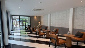 A modern lobby with leather seating, a glass partition, and a brick wall. - The Kite Hotel Bangkok (Bangkok)