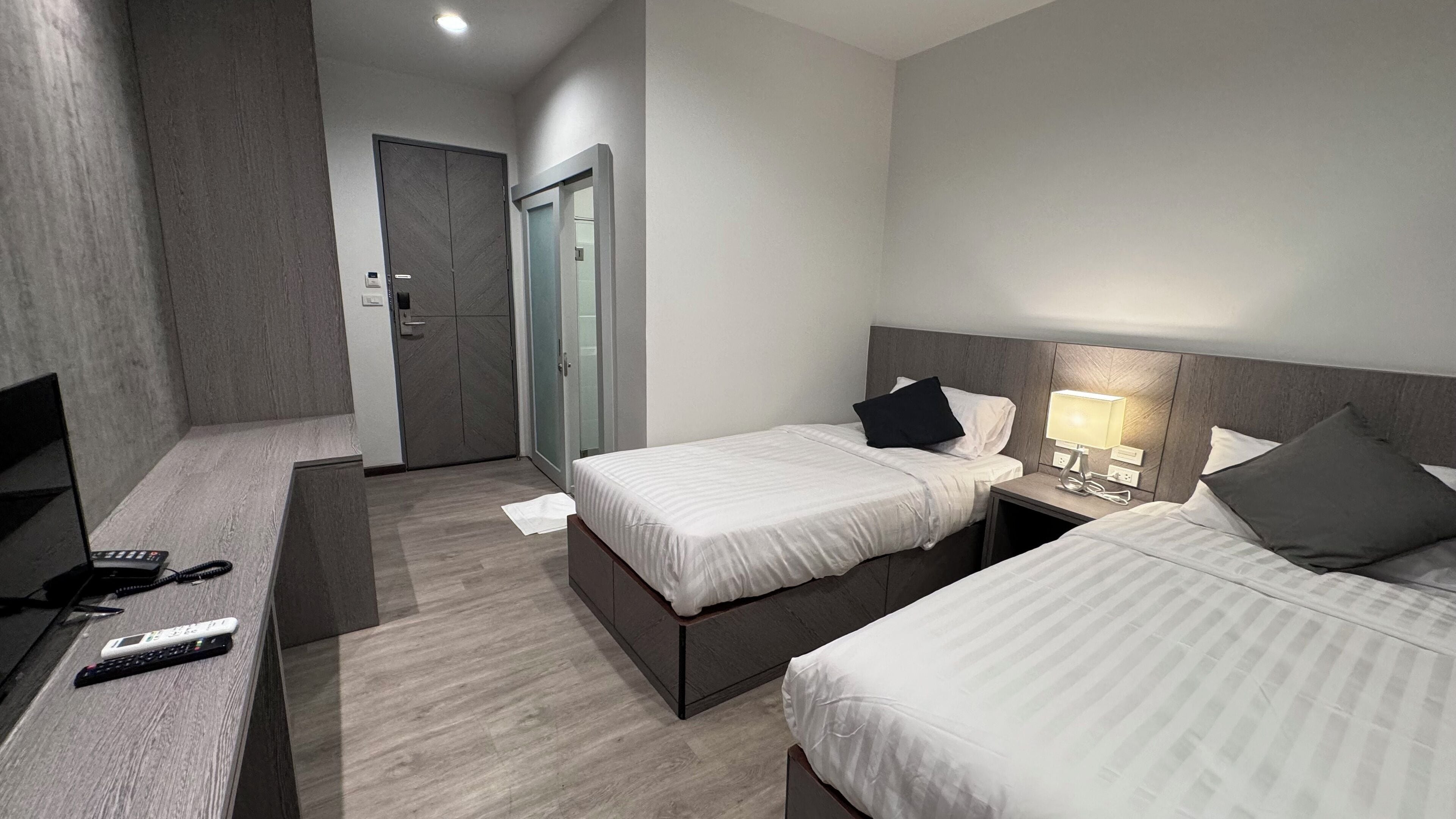 A hotel room with two beds, a desk with a TV, and a wardrobe.