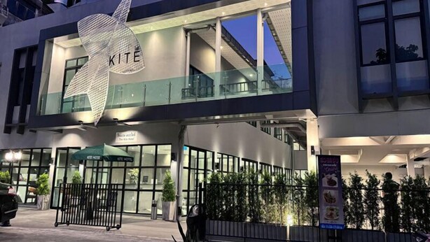 A modern hotel with a large 'KITE' sign, glass railings, and a gated entrance. - The Kite Hotel Bangkok (Bangkok)