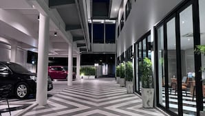 A modern indoor parking area with a checkered floor pattern, large windows, and potted plants. - The Kite Hotel Bangkok (Bangkok)