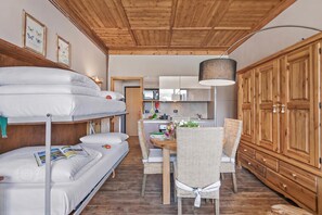 A compact room with bunk beds, a dining area, and wooden cabinets. - Studio Charming Sportinia Town Center (Sauze d'Oulx)