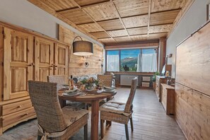 A wooden interior with a dining table, wicker chairs, and a view of mountains. - Studio Charming Sportinia Town Center (Sauze d'Oulx)